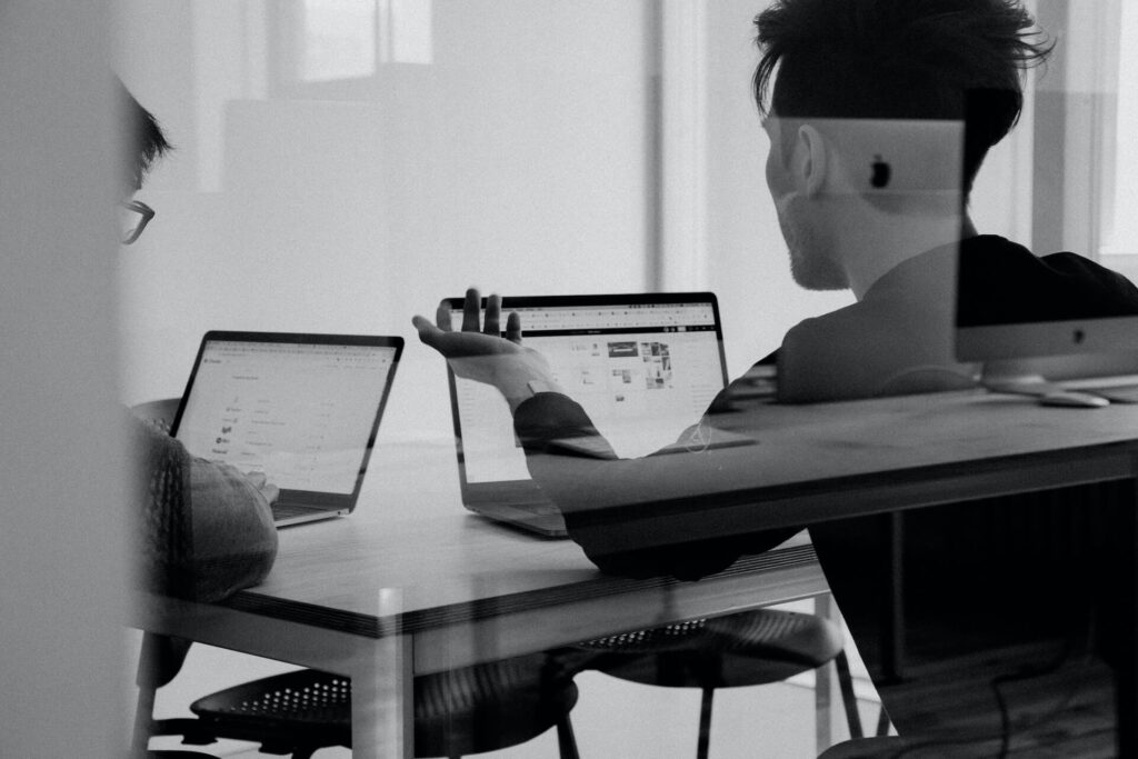 Black and white photo of two people meeting with laptops
